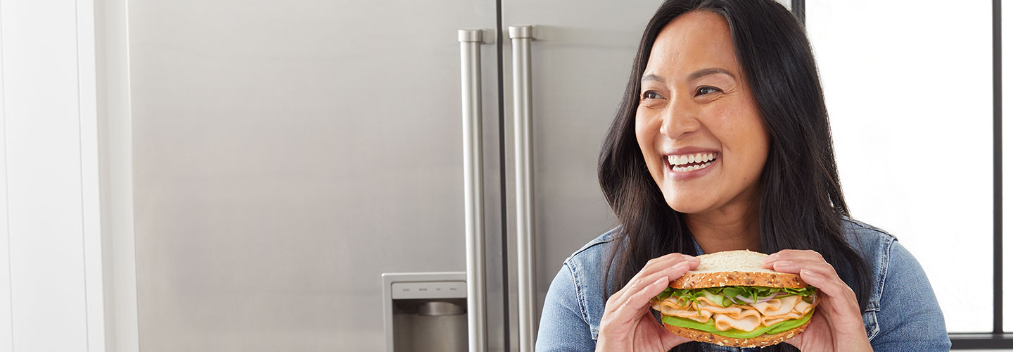 woman eating chicken sandwich in her kitchen